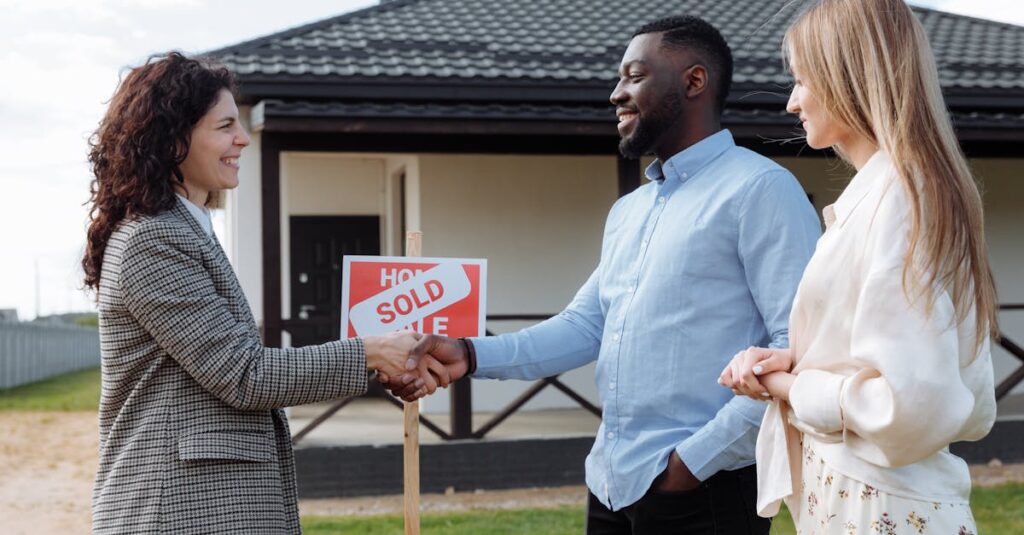 Real estate agent sealing a deal with a diverse couple in front of their new house.